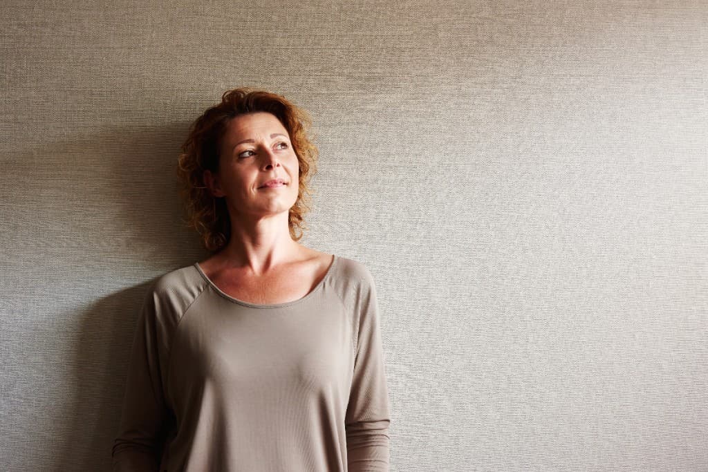 Woman relaxing at home against a neutral wall